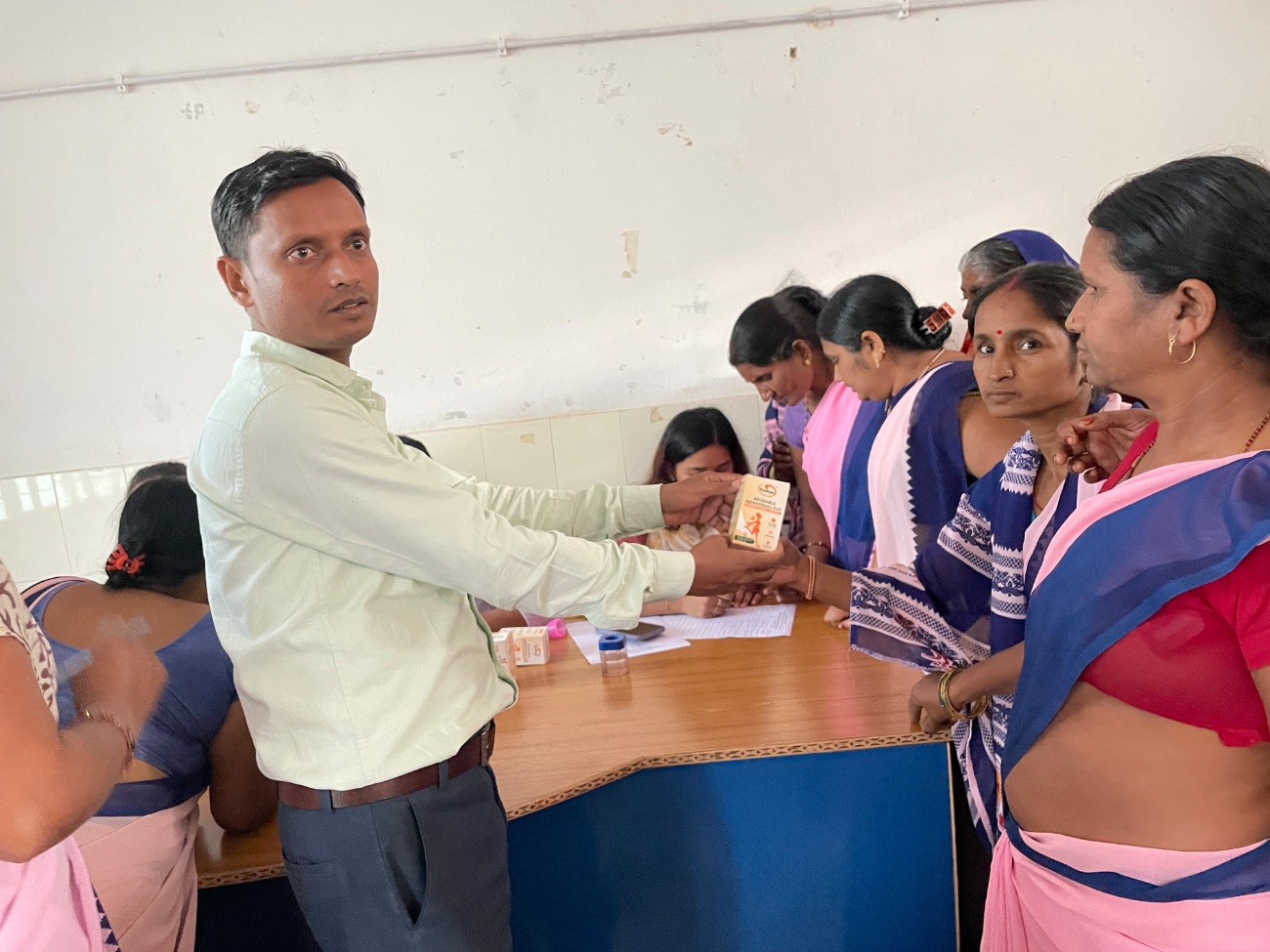 An MJWF volunteer hands a free menstrual cup to women during a distribution session.