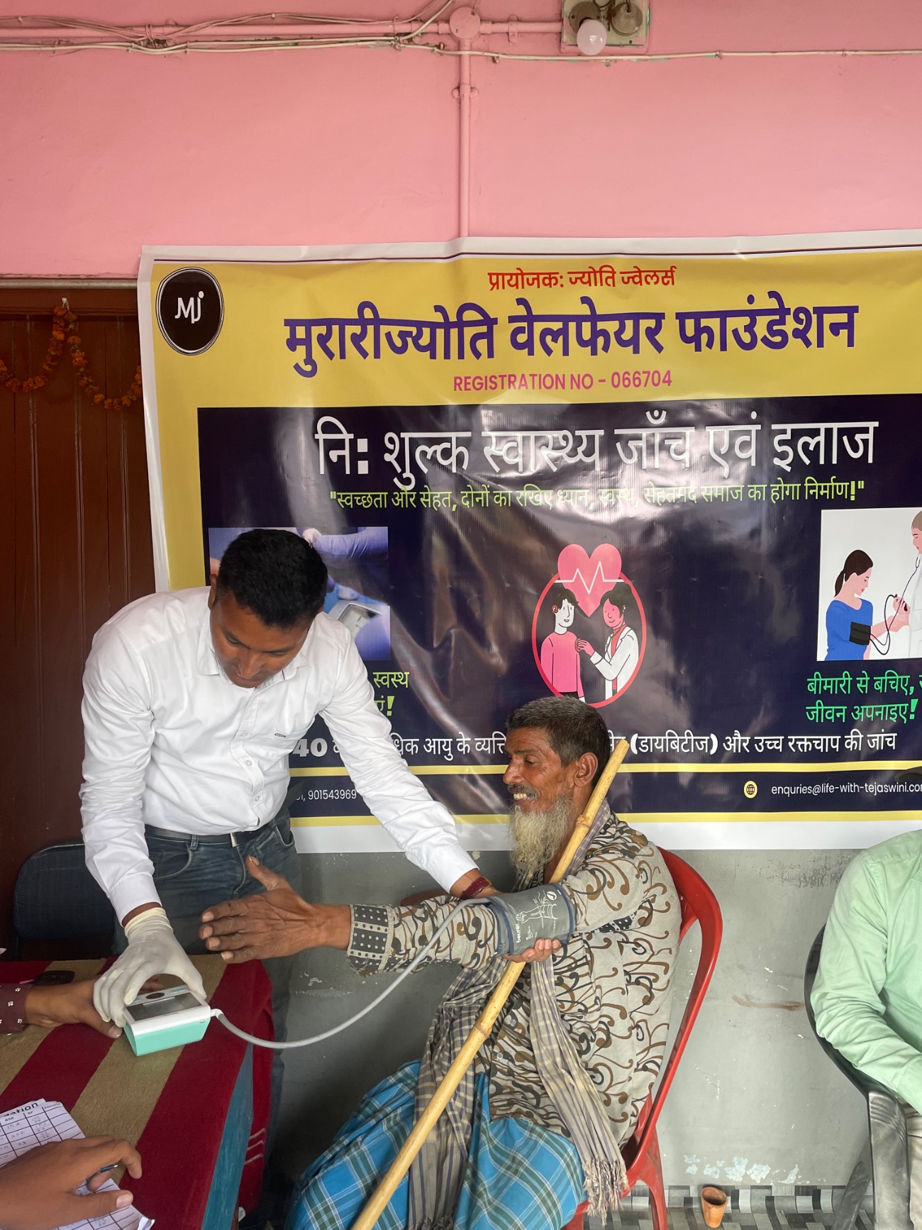 An older man smiles during a free blood pressure check at an MJWF camp.