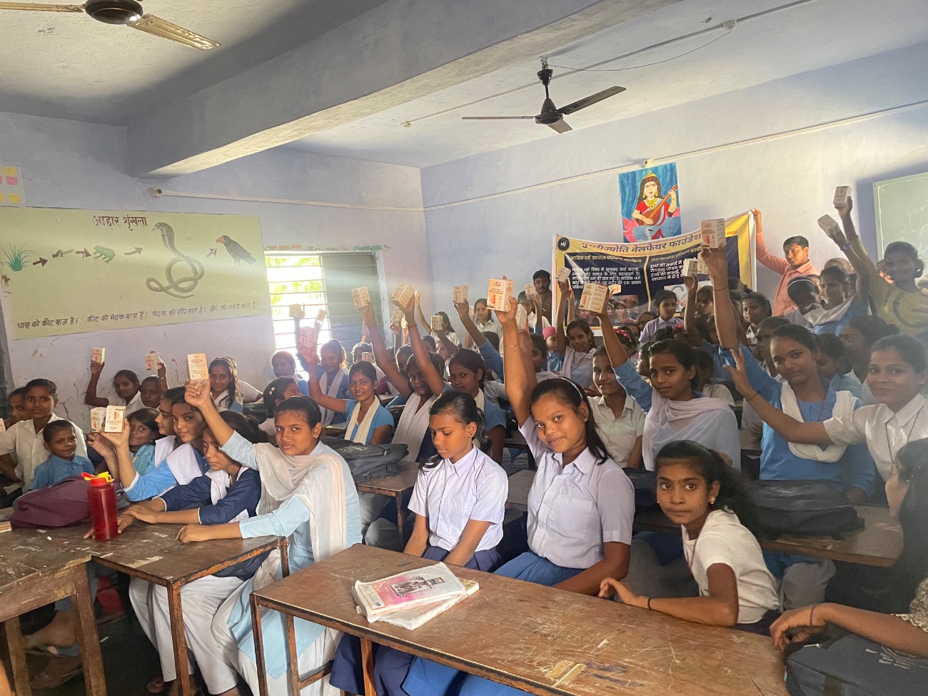 Schoolgirls raise their new menstrual cups in a classroom.