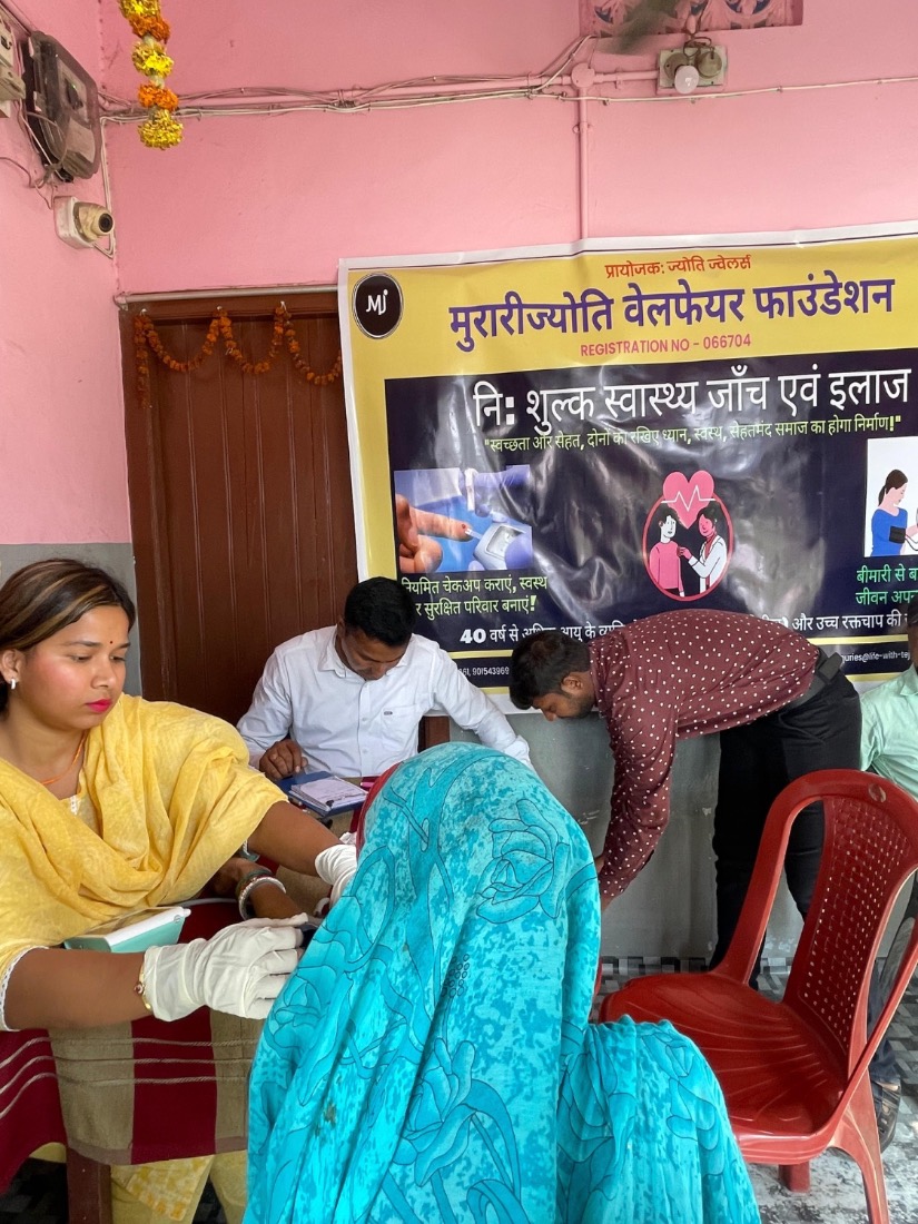 A health worker checks a woman's blood pressure at a free MJWF community health camp.