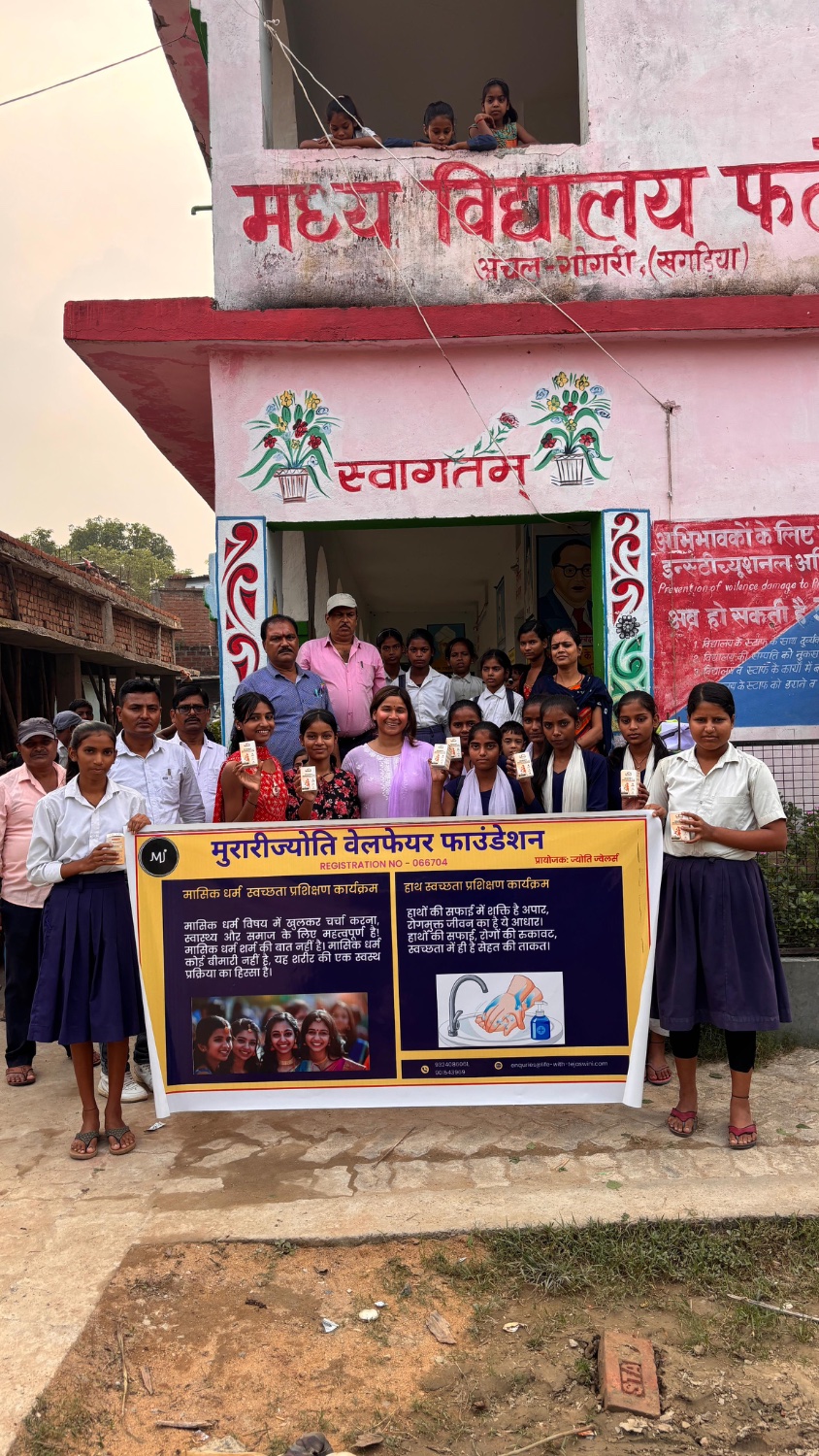 The MJWF founder, teachers and schoolgirls hold the foundation's hygiene and menstrual health banner outside their school in Gogri.
